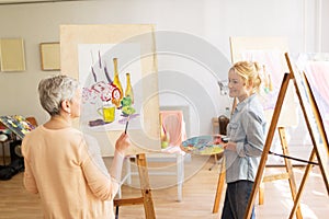 Artist women with easels painting at art school