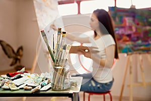 Artist Working On Painting In Studio. Background image, selective focus on foreground