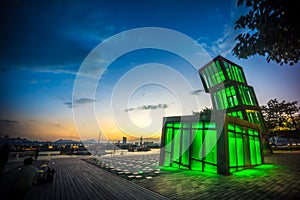 Artistic abstract architecture tower at Kwun Tong Promenade, an urban waterfront park, across skyline and nightscape at sunset