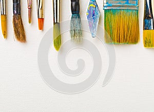 Artistic art supply utensils with brushes on white canvas background with copy space flat lay top view from above