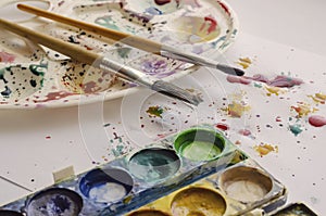 Artistic brushes, a set of paints on a splattered watercolor table