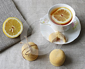 Artistic composition of tea with lemon in white porcelain cup and lemon cookies