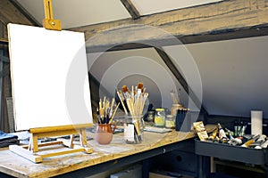 Artistic equipment in a artist studio: empty artist canvas on wooden easel and paint brushes Retro toned photo copy