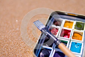 Artistic equipment: paint brushes, watercolors paintings on sand background at sunny summer day - creation, drawing and freedom co