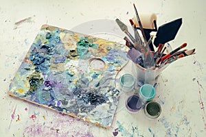 Artistic equipment: painter palette, paint brushes, paints and palette knifes.