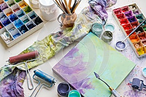 Artistic equipment in studio: canvas, palette knife, paint brushes, paints and palette.