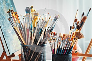 Artistic equipment in studio: painting, easel, paintbrushes and paints.