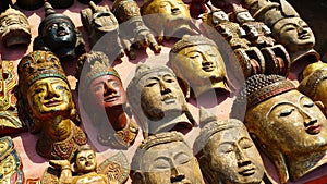 Artistic and exotic wood-carved Buddha faces are displayed at a market stall in Thailand, Asia