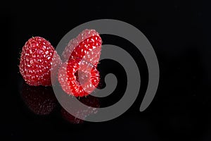 Artistic fresh raspberries reflection on a black reflective surface. Raspberry with black background