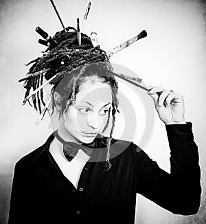 Artistic girl with dreadlocks and bow tie with brushes in dreadlocks