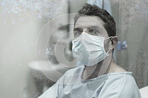 Artistic hospital portrait of attractive and scared man infected by covid19 -  adult male in face mask at clinic suffering