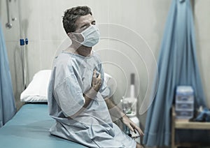 Artistic hospital portrait of attractive and scared man infected by covid19 -  adult male in face mask at clinic suffering