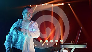 Artistic male disk jockey mixing music track at turntable illuminated nightclub party slowmo