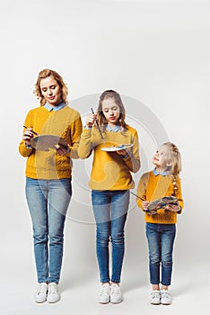 artistic mother and daughters with paint brushes and palettes photo