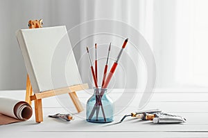 Artistic paintbrushes, canvas on easel and tubes of paint