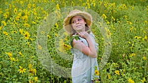 Artistic teenager girl in hat and sunflowers in hands posing on blooming field in countryside. Cute girl standing half