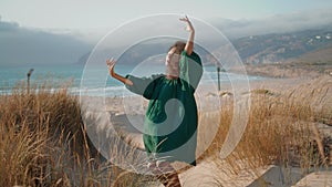 Artistic woman dancer performing sensual dance on sand seashore. Girl dancing.