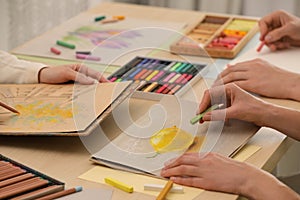 Artists drawing with soft pastels and pencils at table, closeup