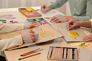 Artists drawing with soft pastels and pencils at table, closeup