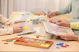 Artists drawing with soft pastels and pencils at table, closeup