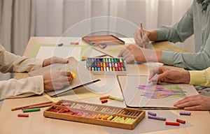 Artists drawing with soft pastels and pencils at table indoors, closeup