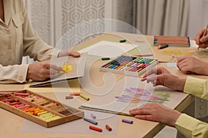 Artists drawing with soft pastels and pencils at table indoors, closeup