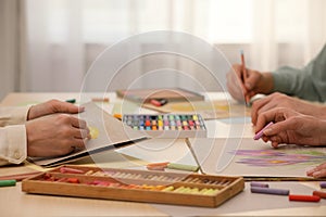 Artists drawing with soft pastels and pencils at table indoors, closeup