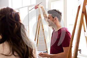 Artists with easels painting at art school