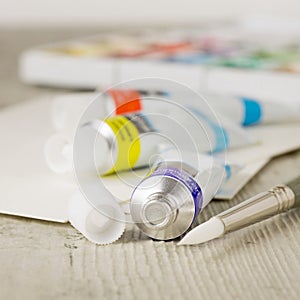 An artists paintbrush with tubes of paint