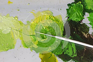 artists white brush and green acrylic oil paints on artistic palette.