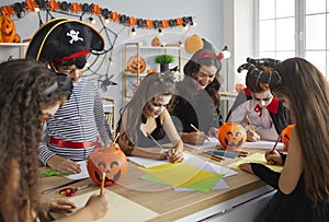 Arts and Crafts teacher and children dressed up in costumes having fun class on Halloween