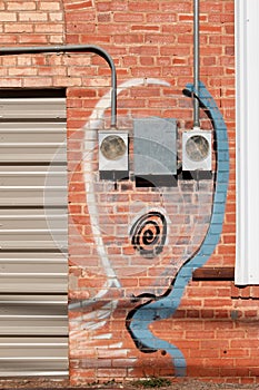 Artwork around meter boxes on red brick wall