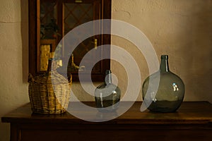 Artwork table decoration with big empty wine bottles, Nostalgic living room with furniture and old mirror, half-dark evening
