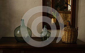 Artwork table decoration with big empty wine bottles, Nostalgic living room with furniture and old mirror, half-dark evening