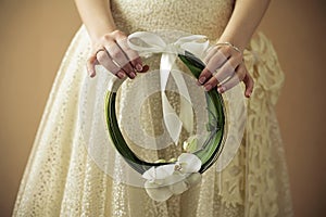 Arty wedding bouquet made of white orchids like a ring with beige ribbon. Daylight. Close up. Studio shot