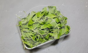 Arugula salad in the plastic box. Rucola lettuce healthy food. Vegetarian lifestyle concept. Green fresh vitamins