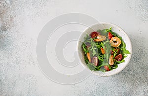 Arugula, tomatoes and shrimps salad on blue stone background