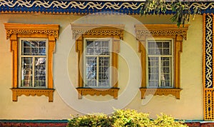 Ð¡arved wooden platbands on three yellow windows of traditional Ukrainian village house.