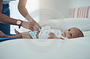 As clean and dry as baby should be. a woman changing her adorable baby girls diaper on the bed at home.