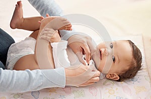 As cute as a button and clean as a whistle. a woman changing her adorable baby girls diaper at home.