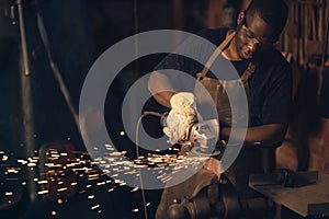 .As in life, the successful forge on. a young man using an angle grinder while working at a foundry.
