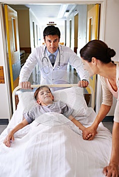 As long as moms here Ill be fine. Shot of a doctor wheeling a young patient down a corridor.