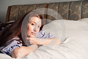 As morning light filters in, a woman lies in serene contemplation, embracing the quietude of bedroom