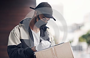 As safe and efficient as a delivery service should be. a masked young man delivering a package to a place of residence.