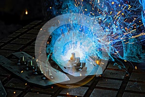 As worker welding using gas argon to steel light sparks are created that smoke in factory at a work