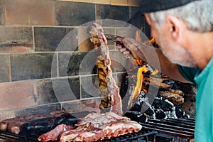 Asado. Argentinian mature man making a barbecue in the grill of his house. photo