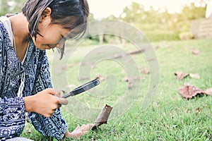 Asain girl hand holding magnifying glass in garden