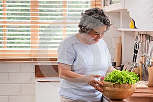 Asain senior woman preparing vegetables  salad in the kitchen. Healthy meal concept.Aging at home