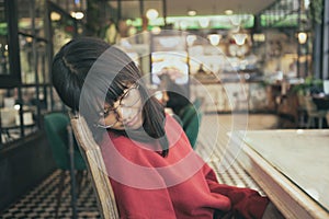 Asain teenager take a nap while sitting in cafe room