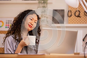 Asain woman sips coffee in the morning and wakes up with a white cup of coffee. Relaxing on weekends